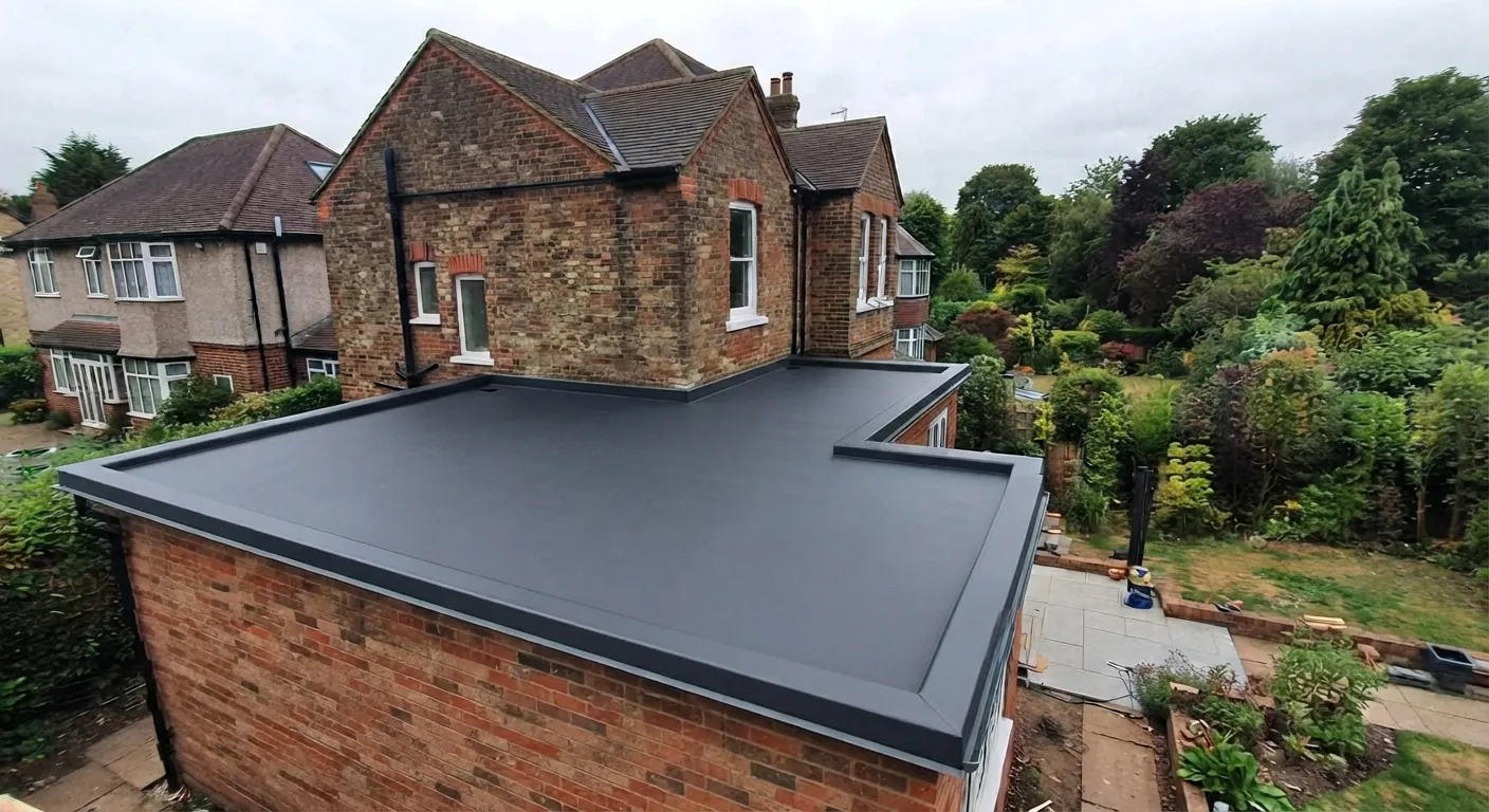 Completed charcoal GRP flat roof wrapping an L-shaped single-storey extension, with dark grey drip trims all the way round